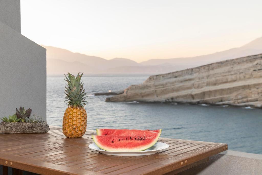 einen Tisch mit Ananas und zwei Stücken Wassermelone in der Unterkunft Stelios Apartment in Matala