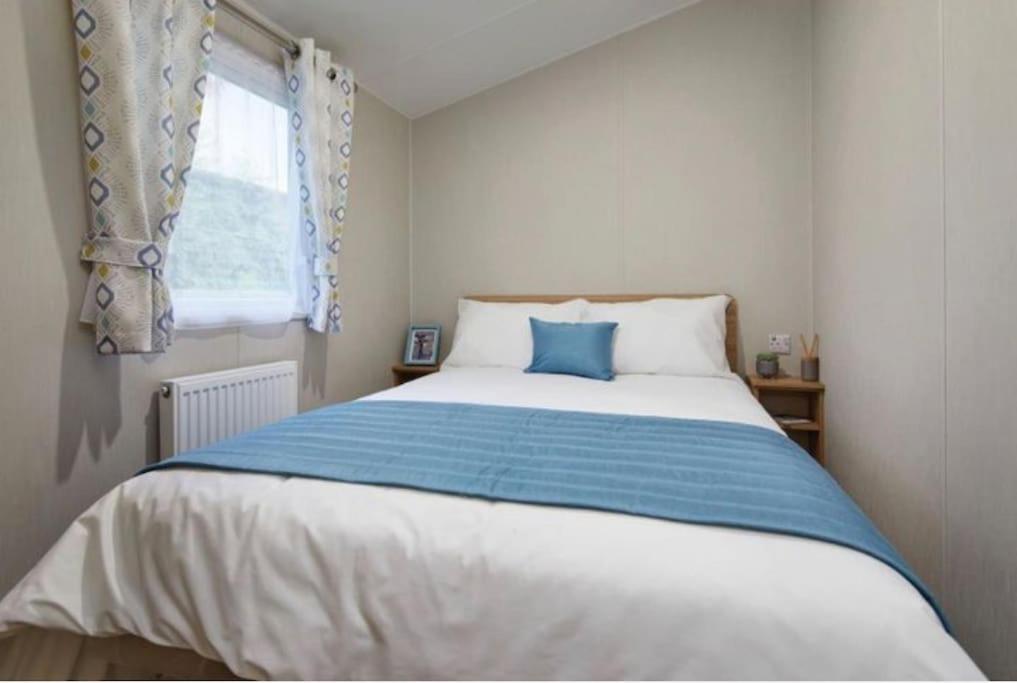 a bedroom with a bed with a blue and white blanket at Lancaster Views, Luxury 2022 home with Hot Tub in Tattershall