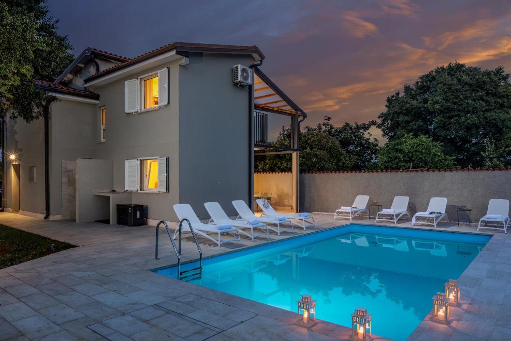 een zwembad met stoelen en een huis bij Villa Pietra in Brtonigla