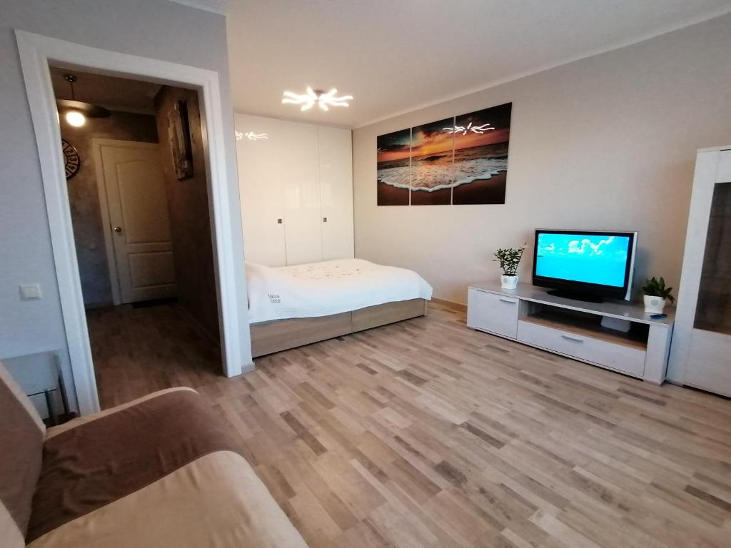 a living room with a bed and a flat screen tv at Jurmala Kauguri in Jūrmala