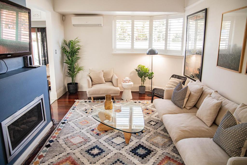 uma sala de estar com um sofá e uma lareira em Elegant Federation Home Near The Airport em Sydney
