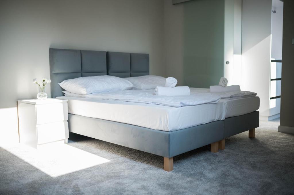 1 dormitorio con 1 cama grande con sábanas blancas en Apartamenty Wielbarska, en Szczytno