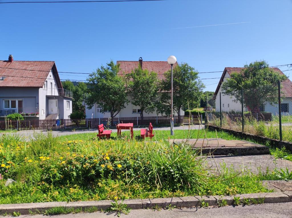 two red benches in a park with houses in the background at Veranda in Saborsko