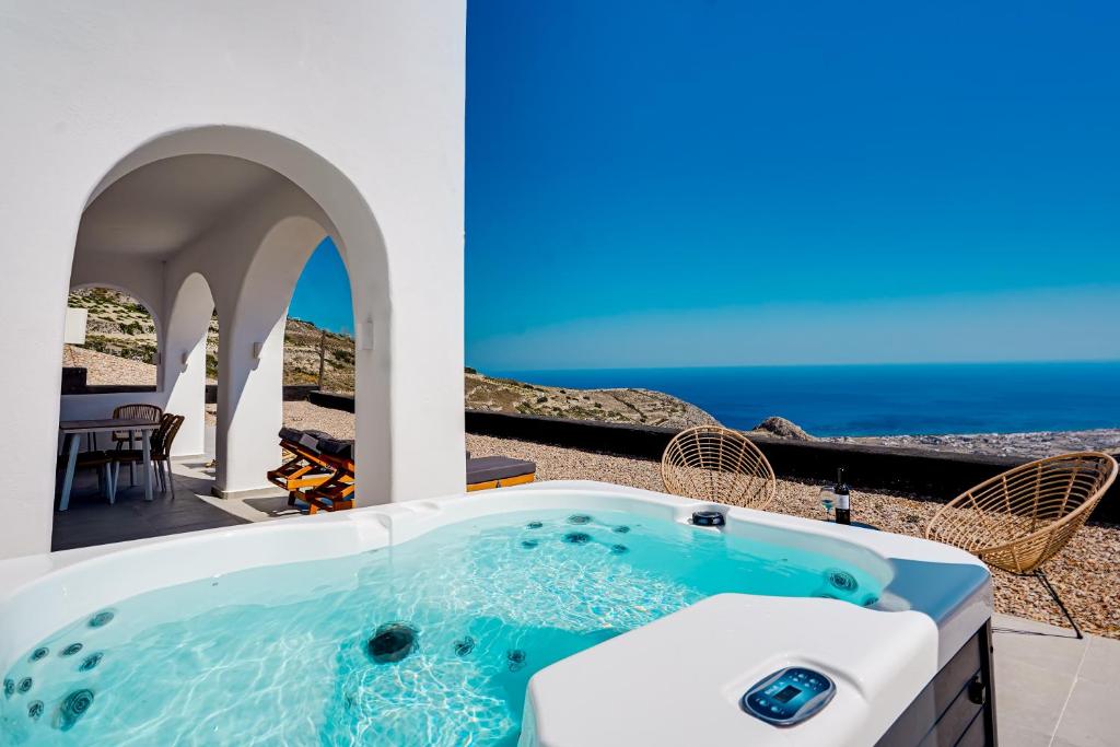 a hot tub on a patio with the ocean in the background at Acria Villas in Pyrgos