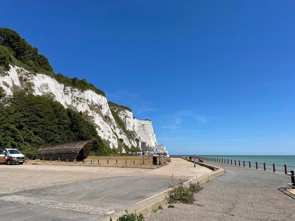 a road next to a beach with a white cliff at Peaceful holiday home on a park on the Kent Coast in St Margarets at Cliff