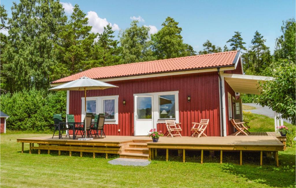 um chalé vermelho com um deque e cadeiras em Awesome Home In Malmkping With Kitchen em Malmköping