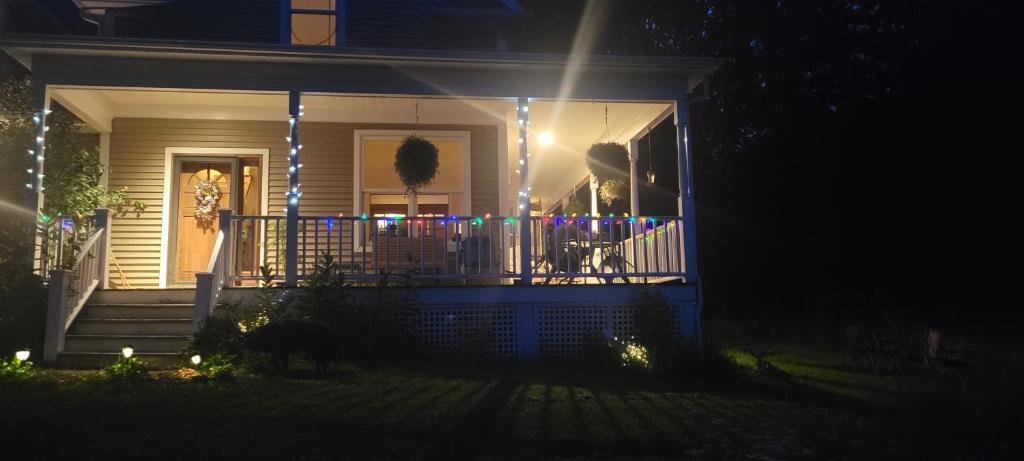 a house with lights on the front porch at night at Front of Country shabby chic Home near Ganondagan Historic Site on 10 wooded acres in Victor