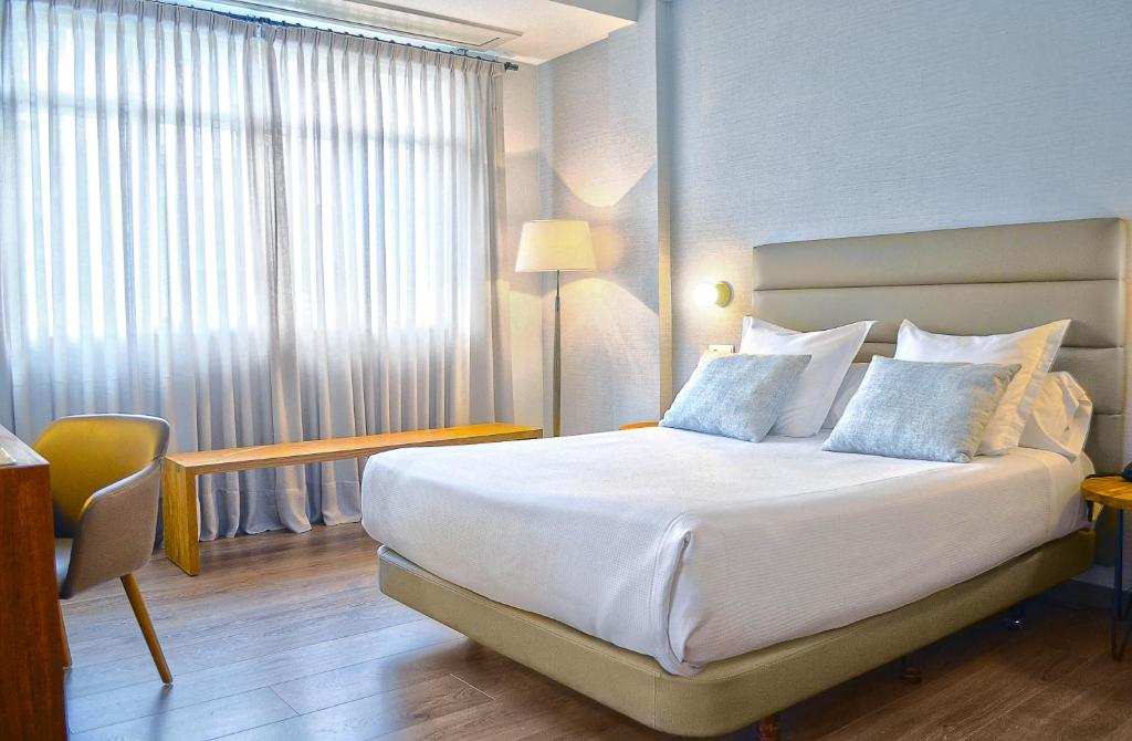 ポンテベドラにあるRias Bajasのベッド、デスク、窓が備わるホテルルームです。