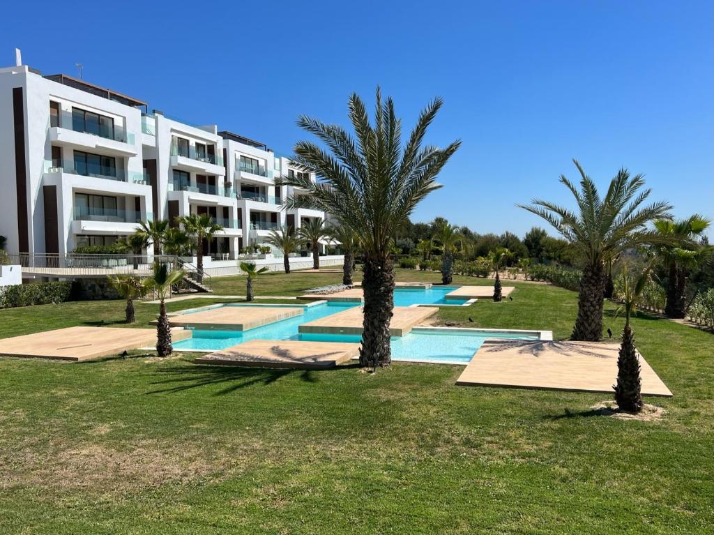 ein Resort mit Palmen vor einem Gebäude in der Unterkunft 3-bed room appartement at Las Colinas Golf & Country Club in Orihuela