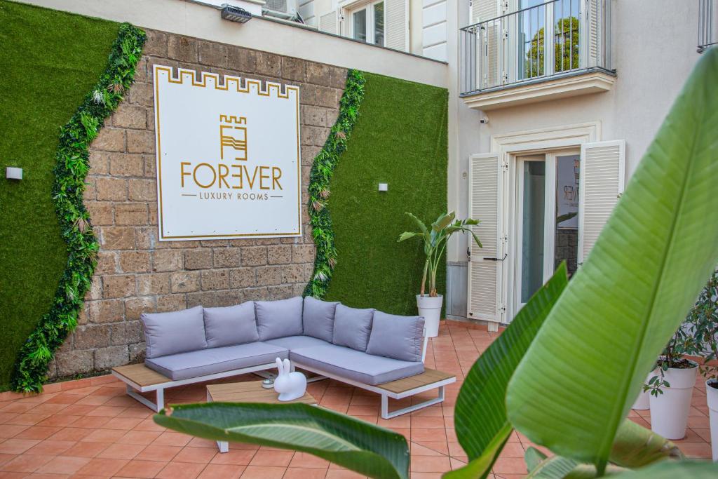 een bank op een patio met een muur met planten bij Forever Luxury Rooms in Castellammare di Stabia