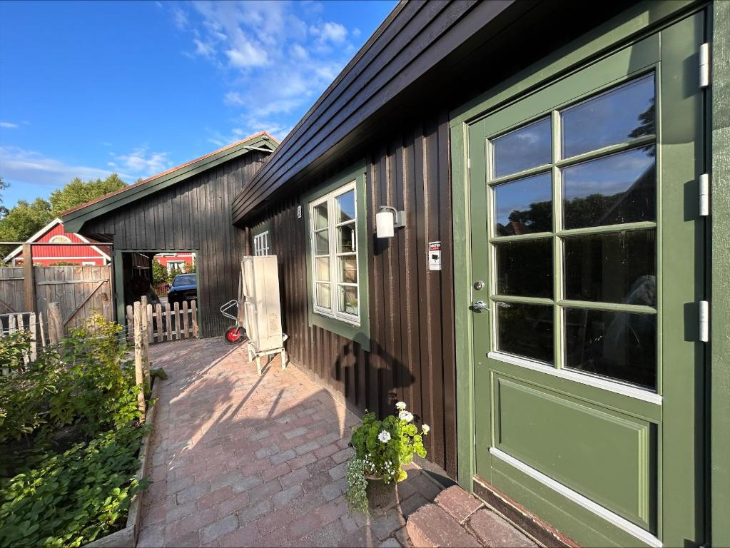 a house with a green door and a patio at Havsbadens B&B in Ängelholm