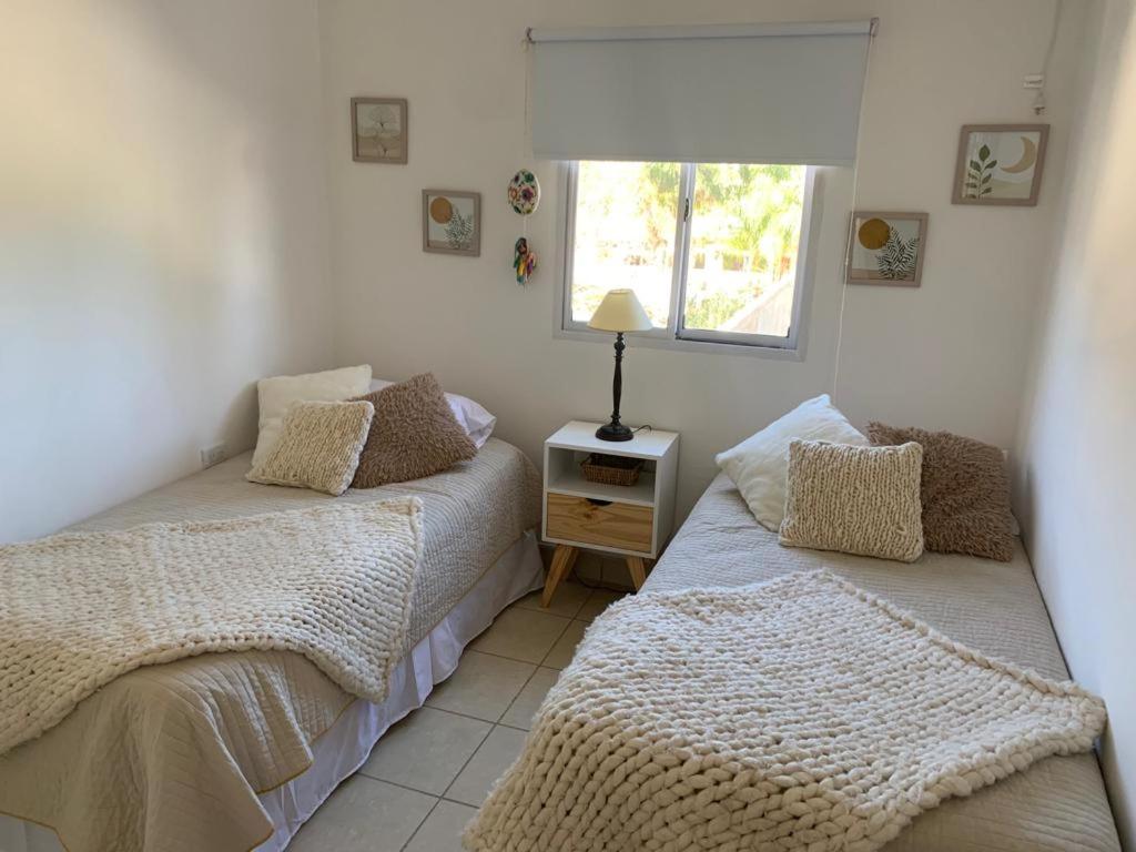 two beds in a room with a window at Departamentos Cristo del Portezuelo in Chilecito