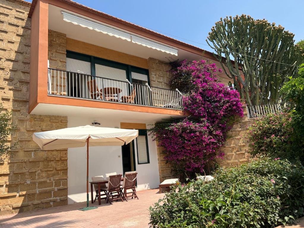 a patio with an umbrella and chairs and a balcony at Appartamentino in villa sul mare in Noto Marina