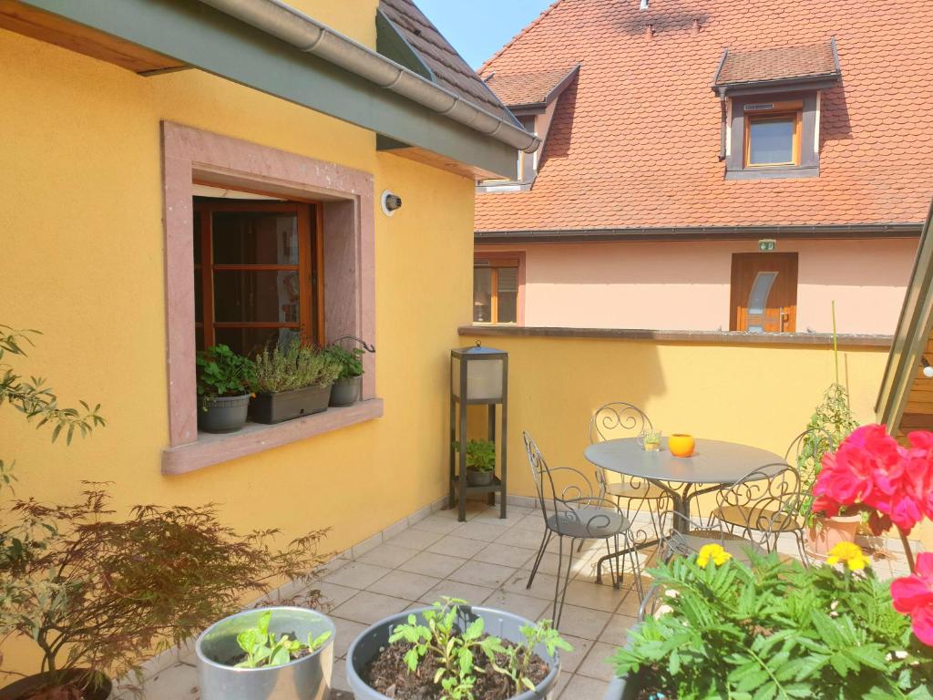 Casa amarilla con patio con mesa y sillas en LE SCHMOUTZ: Charmant duplex entre Colmar et Mulhouse (1-4 pers), en Ensisheim