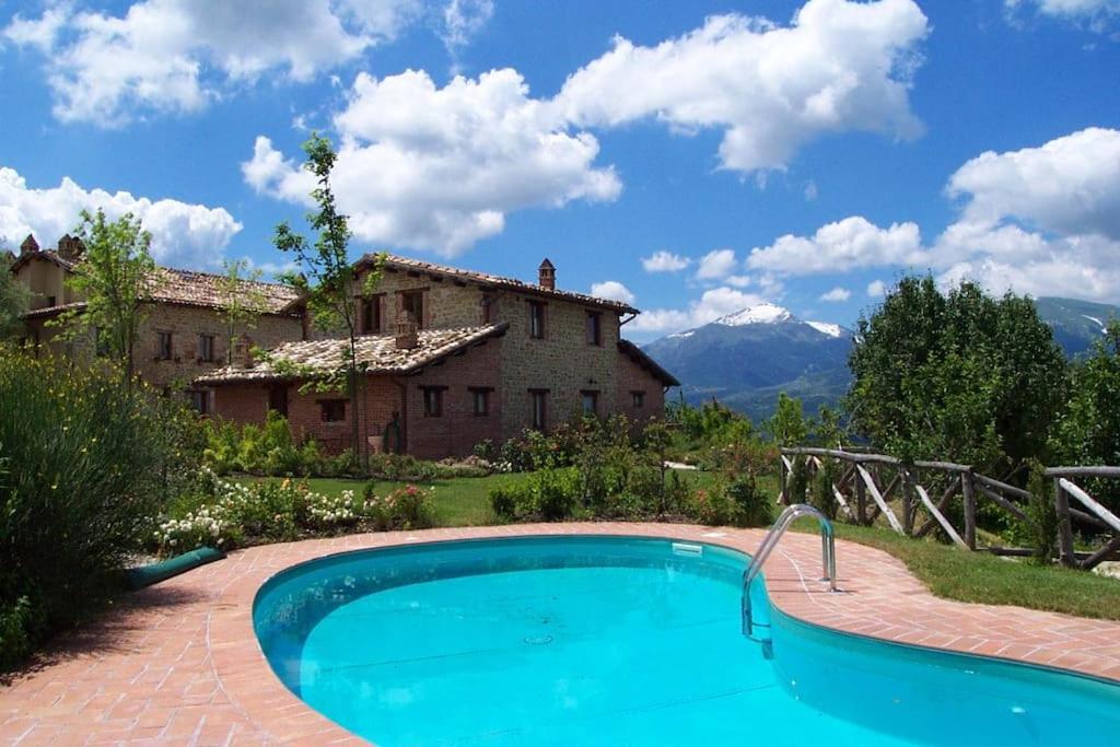 une piscine extérieure en face d'une maison dans l'établissement Casale con vista sui Monti Sibillini e piscina, à Amandola