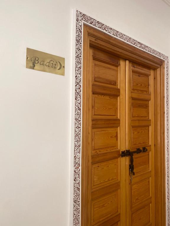 een houten deur met een bord op een muur bij RIAD LA LUNE in Marrakesh