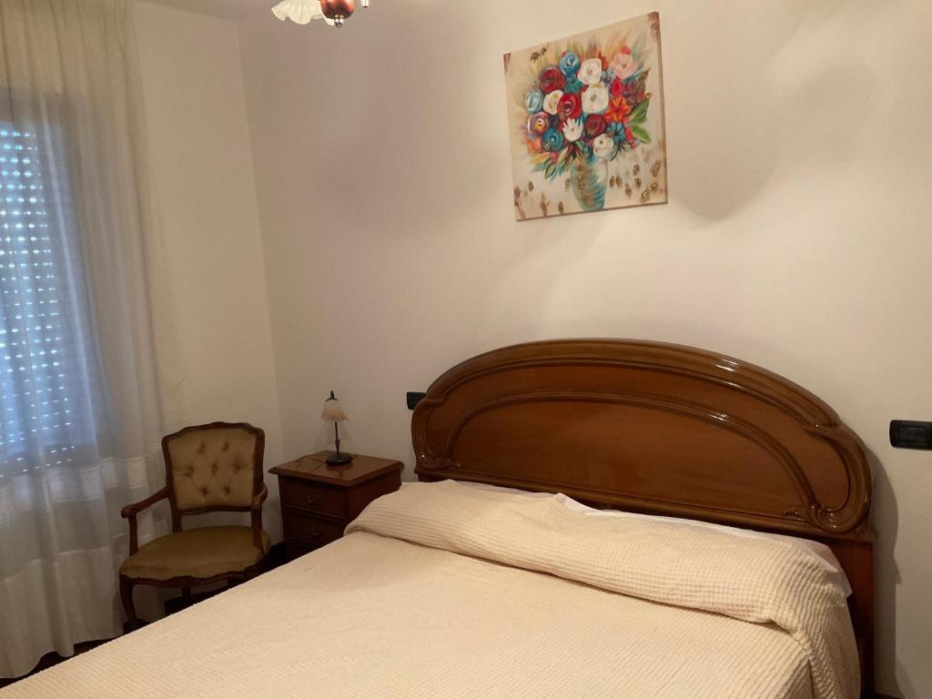 1 dormitorio con 1 cama, 1 silla y 1 pintura en La Primula, en Marsciano