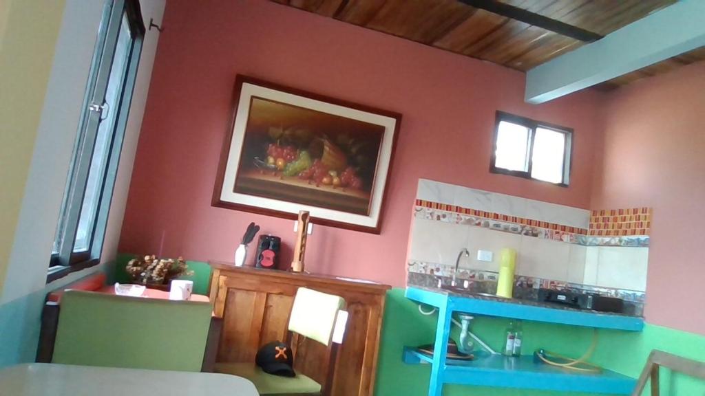 cocina con mesa y paredes de color rosa y verde en villa nabusimaque by 100%Xanahoria, en Marinilla