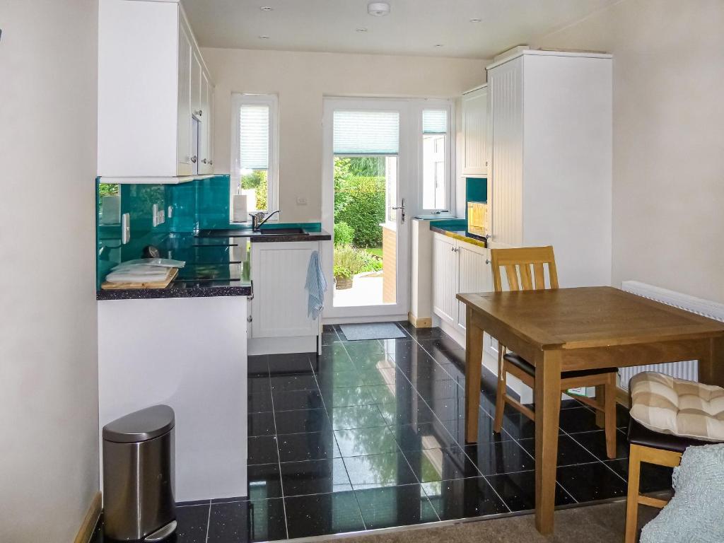 a kitchen with white cabinets and a wooden table at The Annexe in Hereford