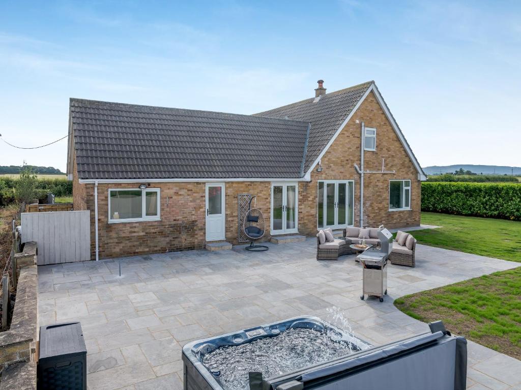 a patio with a hot tub in front of a house at Manor Farm Cottage in Hornby