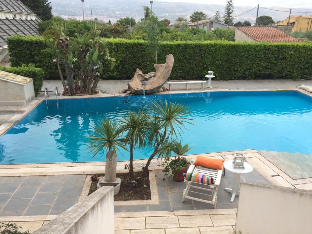 a large blue swimming pool with a table and palm trees at Sicilia Bedda B&B in Vittoria