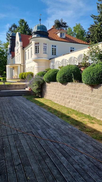 een groot wit huis met een hek ervoor bij Chateau Radvanov Pension in Mladá Vožice