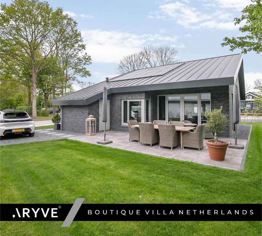 a house with a table and chairs in a yard at VILLA ARYVE in See-, Strand- und Golfplatznähe inklusive NETFLIX, Bad en Suite und Wohlfühlgarantie in Dirkshorn