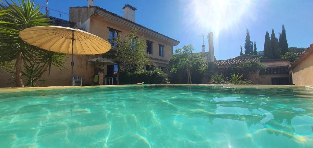 a large swimming pool with an umbrella in front of a house at La Flamenca Inn in Cortelazor