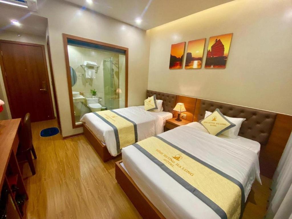 una camera d'albergo con due letti e uno specchio di Khách sạn Đỉnh Hương Hạ Long a Ha Long