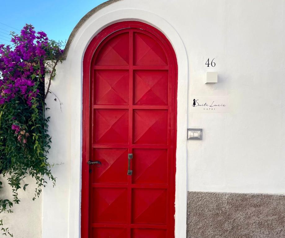 czerwone drzwi na boku białego budynku w obiekcie SUITE LUCIA w mieście Capri
