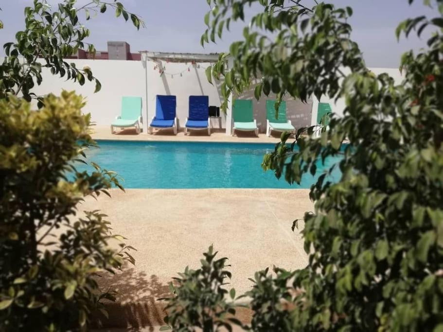 - une piscine avec des chaises longues bleues et vertes dans l'établissement La case ronde avec Piscine -Ndayane, à Ndéyane