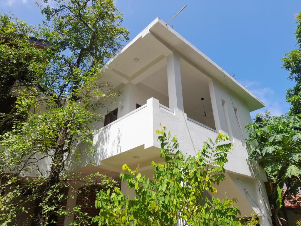 een wit gebouw met bomen ervoor bij Gloria Inn in Negombo