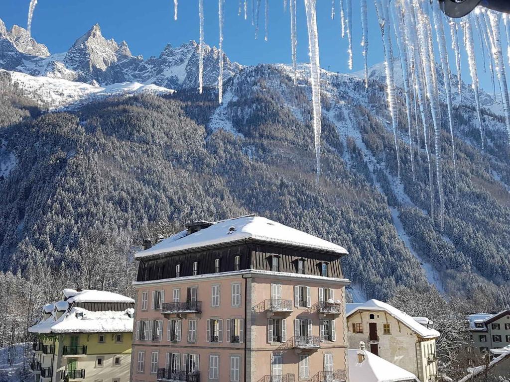 un bâtiment avec de la neige devant une montagne dans l'établissement Appartement Chamonix-Mont-Blanc, 4 pièces, 10 personnes - FR-1-517-37, à Chamonix-Mont-Blanc