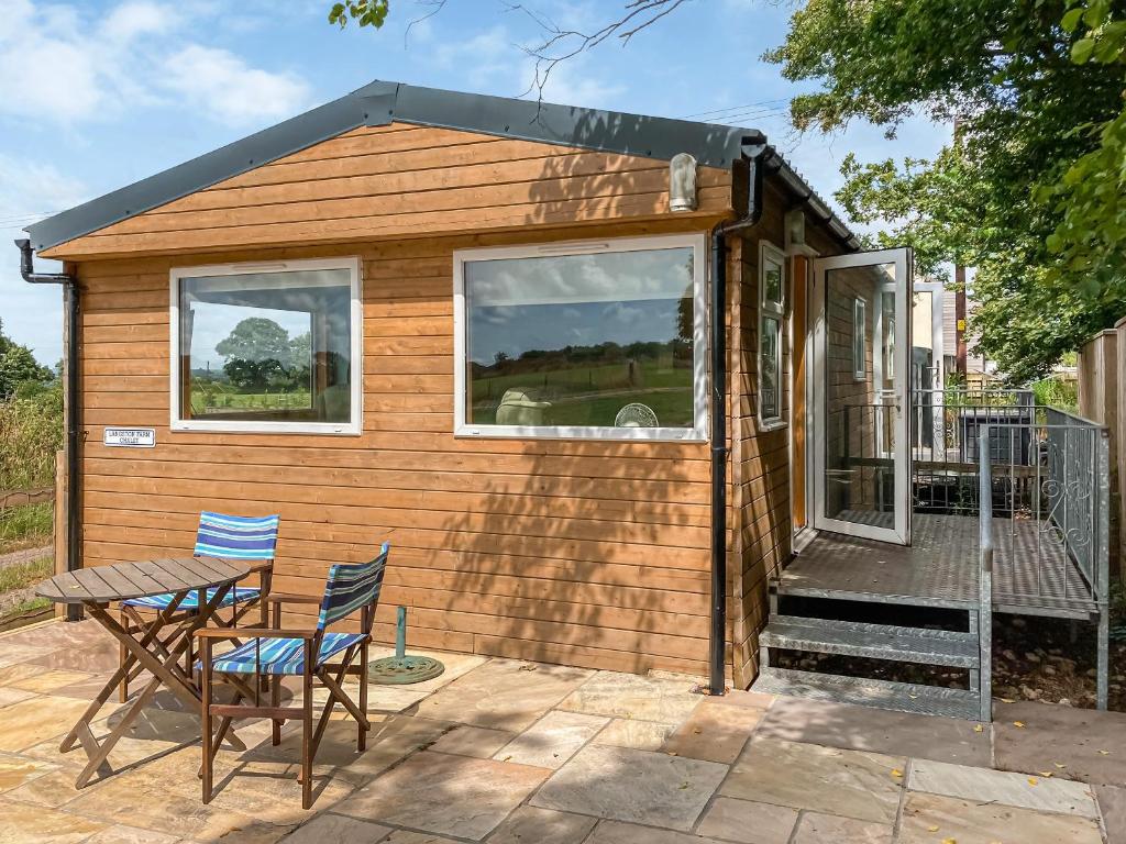 a tiny house with a table and chairs on a patio at Langston Farm Chalet in Shillingstone