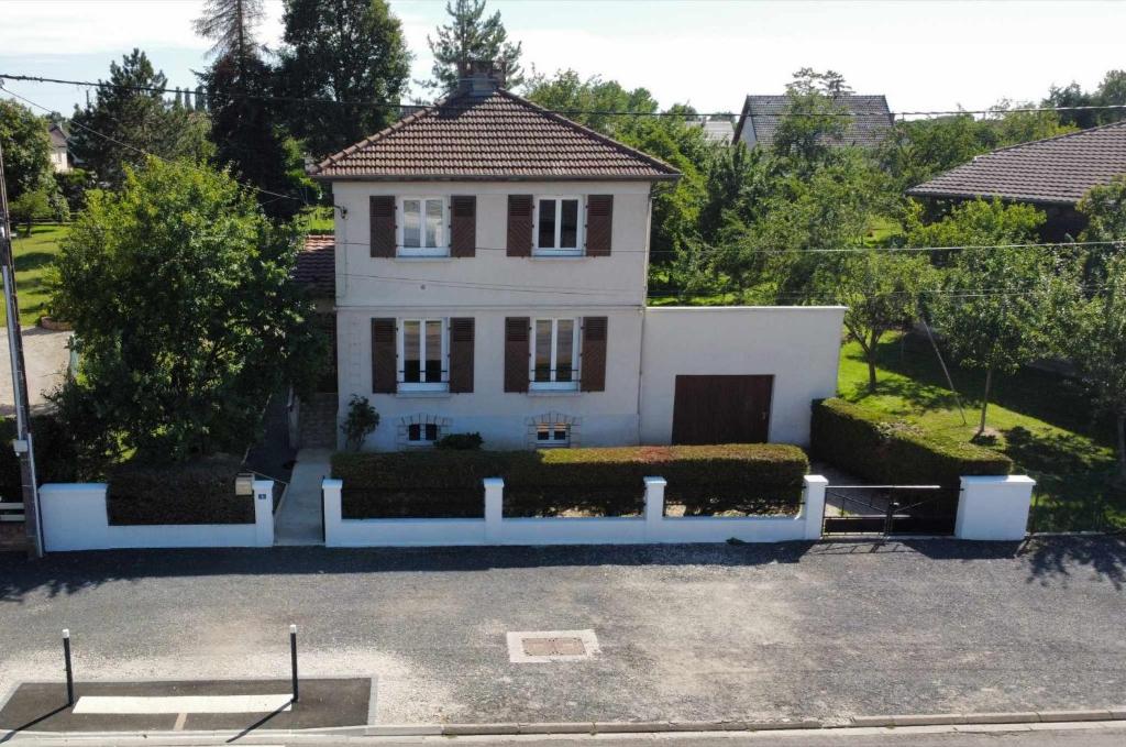 une maison blanche avec une clôture blanche dans un parking dans l'établissement L'échappée Dervoise, à Montier-en-Der