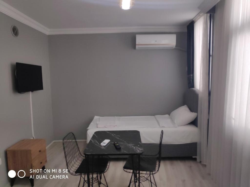 mały pokój z łóżkiem, stołem i krzesłami w obiekcie Palmas Apart w Stambule
