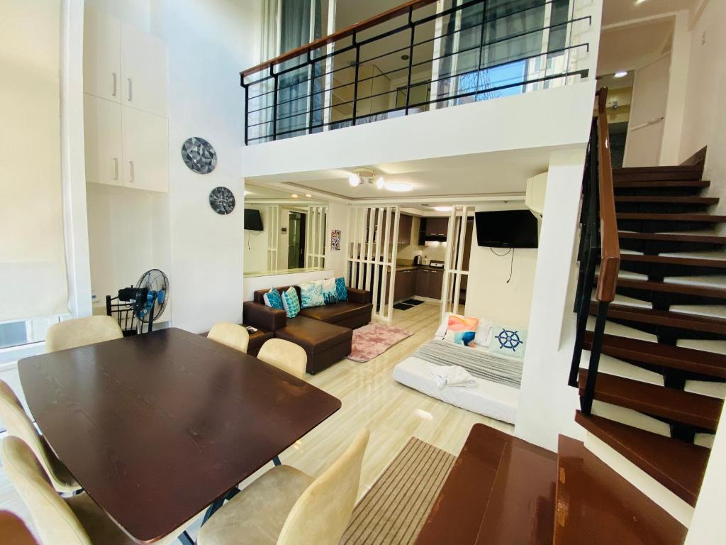 a dining room and living room with a table and a staircase at Cebu City Huge Lofts by P&J in Cebu City