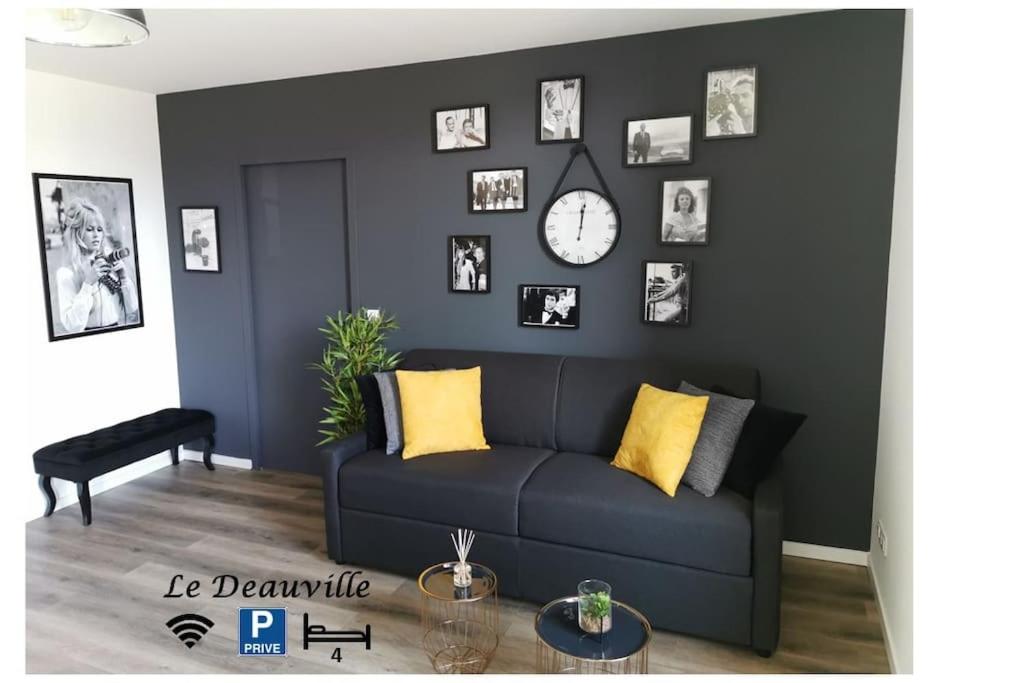 a living room with a blue couch and a wall with pictures at LE DEAUVILLE *T2 (40m²) *WIFI*PARKING PRIVE*CALME in Lourdes