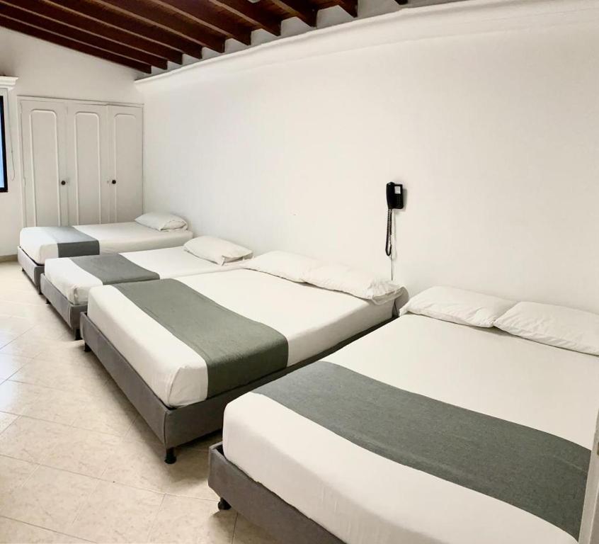 three beds are lined up in a room at Hotel Lukas in Medellín