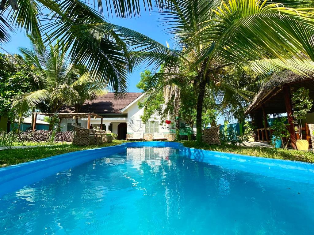 a swimming pool in front of a house with palm trees at Green's Nungwi in Nungwi