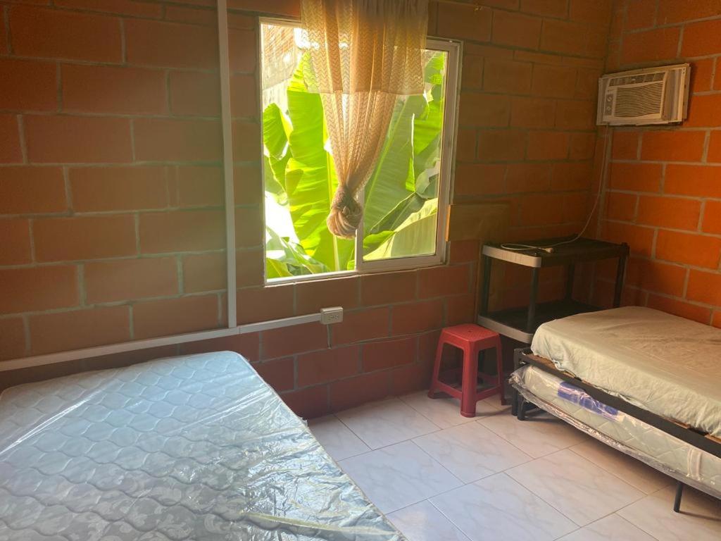 Zimmer mit einem Bett und einem Fenster mit einer Pflanze in der Unterkunft Villa Celeste in Arboletes