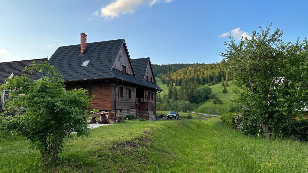 ein Haus auf einem Hügel mit einem Auto daneben geparkt in der Unterkunft Chata Dolina v Bachledke in Ždiar