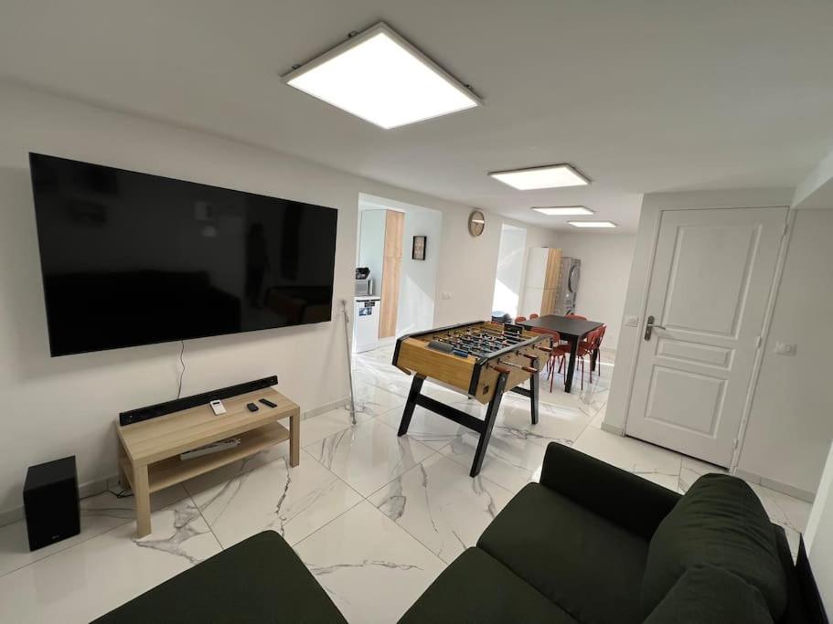 uma sala de estar com um sofá e uma televisão de ecrã plano em Cosy home with babyfoot near Paris & Disney em Noisy-le-Sec