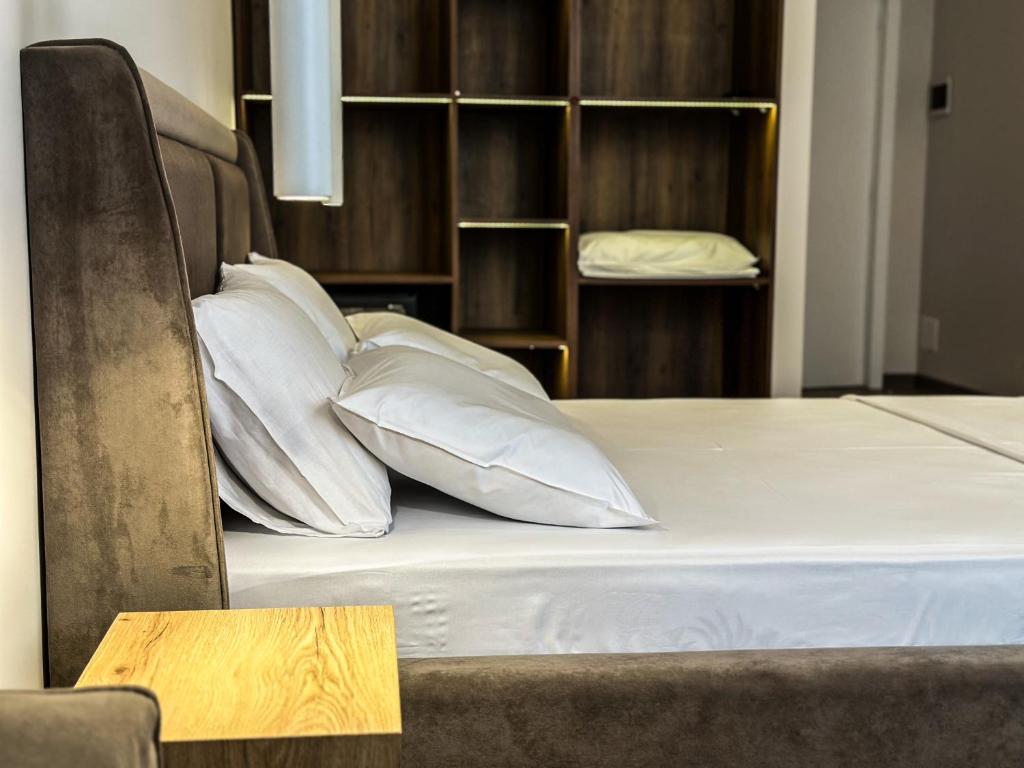 una cama con almohadas blancas encima en ALEXANDER Rooms & Apartments, en Durrës