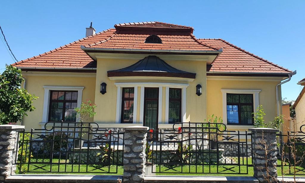 een klein geel huis met een rood dak bij Várkert Deluxe Apartmanház in Miskolc
