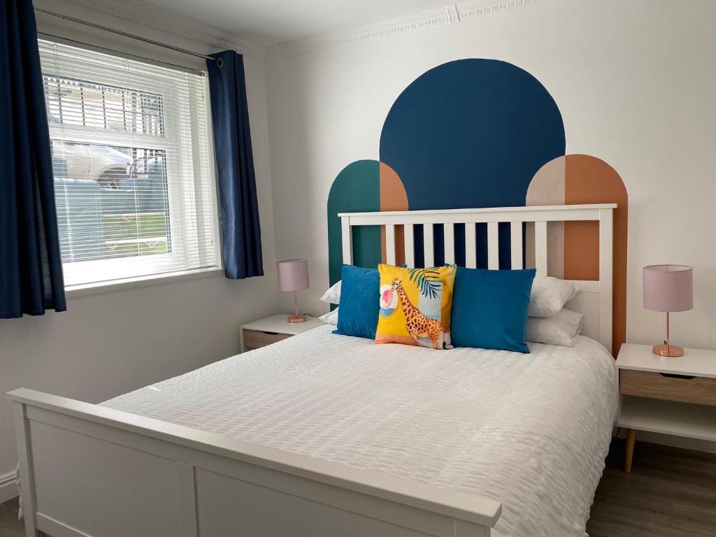 una camera da letto con un letto bianco con cuscini blu e arancioni di Kemptown Courtyard Apartment a Brighton & Hove