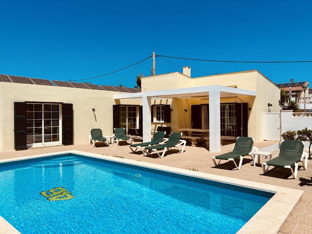 a swimming pool with chairs and a house at Villa Jordi - Cala en Porter in Cala'n Porter