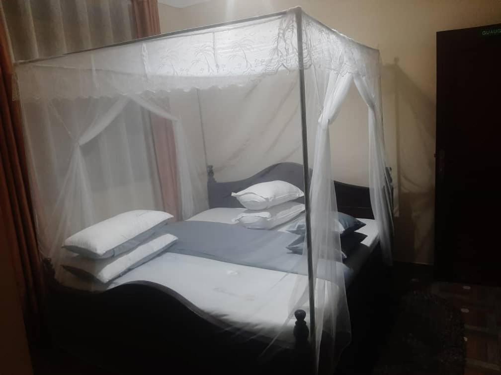 1 dormitorio con cama con dosel, sábanas y almohadas blancas en Starnford Hotel, en Njara