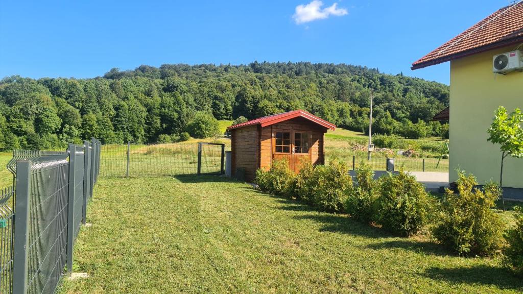 a small wooden building in a field with a fence at House of inspiration above LAKE Sabljaci with pool in Ogulin
