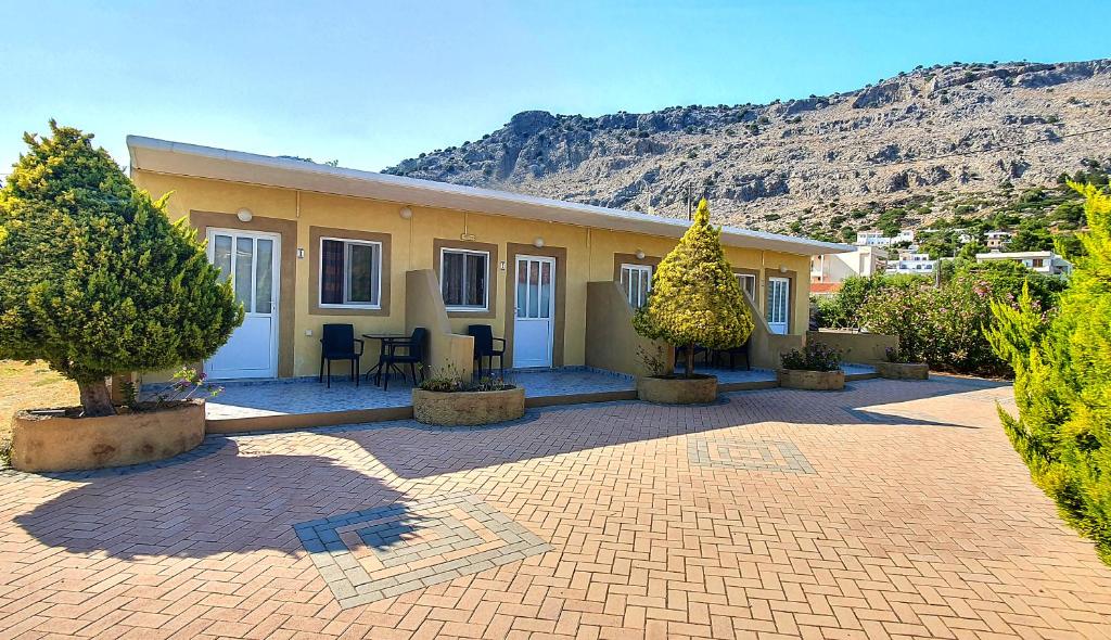 a yellow house with trees in front of it at George Studios Pefkos in Pefki